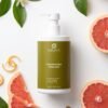 Shampooing Protection Couleur Éclat de Pamplemousse entouré de tranches de pamplemousse et de feuilles vertes, cosmétique naturelle.